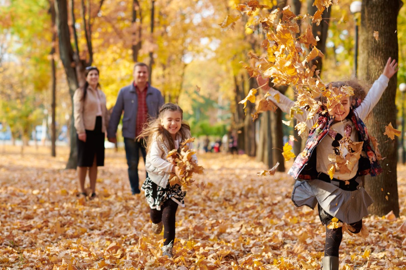 Family walking through fallen leaves during an October holiday