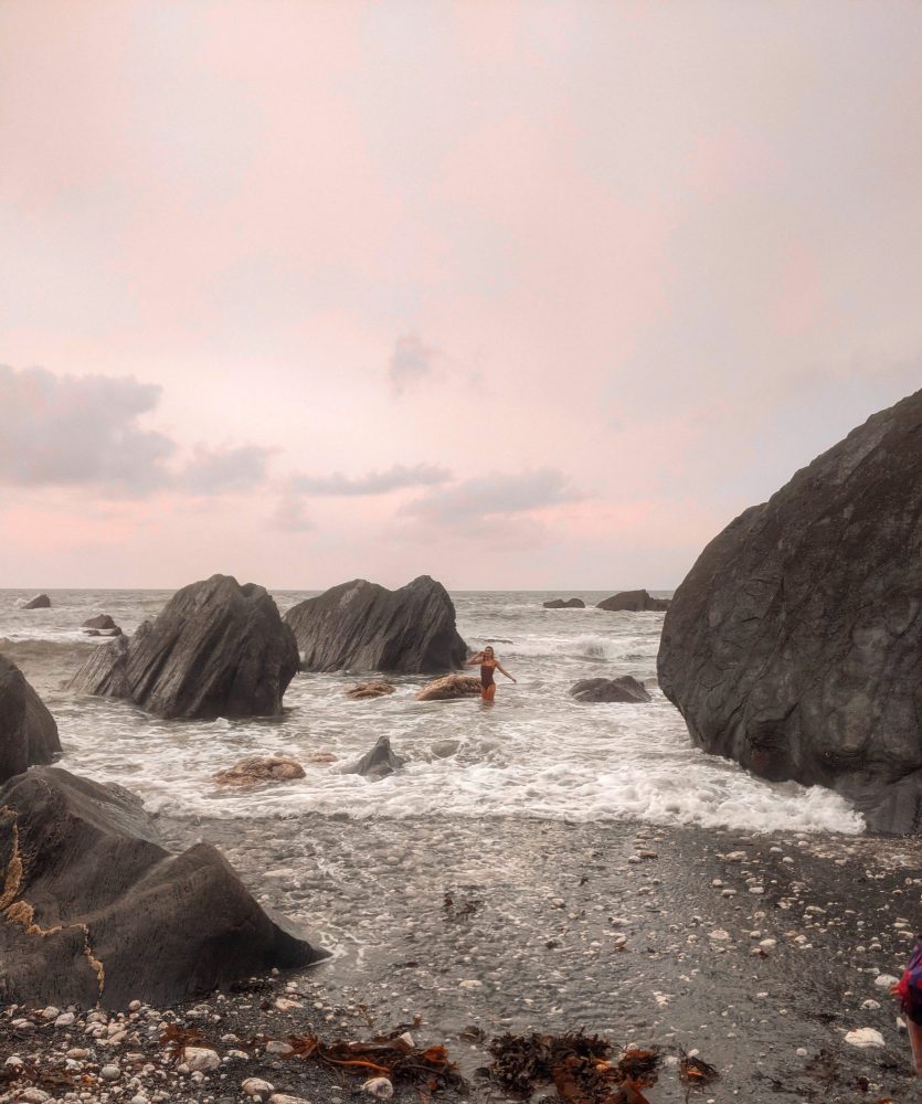 Woman paddling in the sea during cold water swimming on a rocky beach